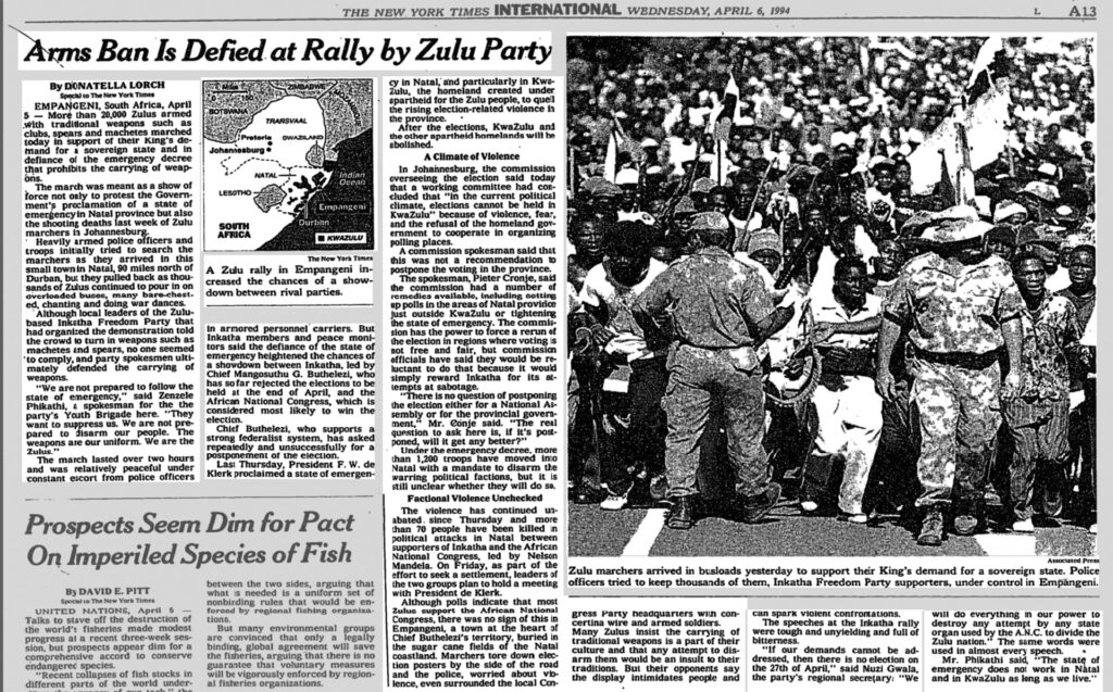 Interior page of the New York Times. In the photograph on the right of the page there is a crowd of Zulus protesters marching in demand of a sovereign state. Two police officers are in the front of the photograph, one facing the direction of the marchers, one facing away from them.