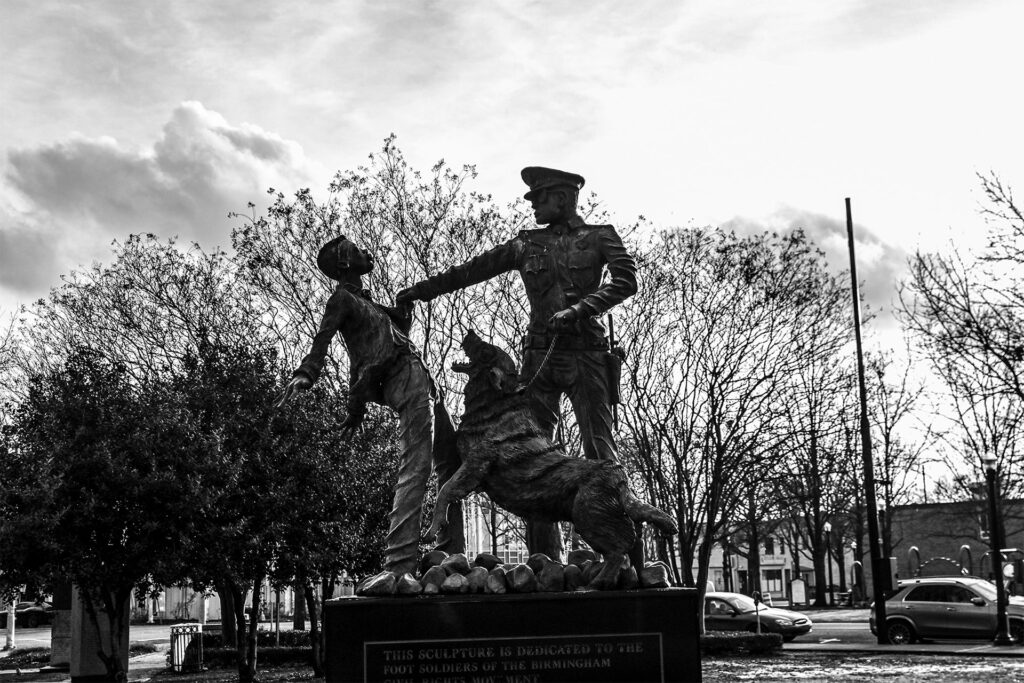 A monument in Birmingham, Alabama. The monument captures the moment of the famous photograph of the teenage boy held by the shirt by a policeman as a German Shepard is in the process of attacking him.